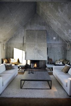 a living room filled with white couches and a fire place in the middle of it