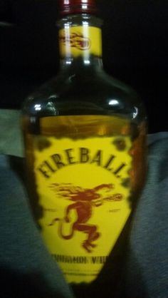 a bottle of fireball rum sitting on someone's lap