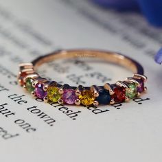 a close up of a ring on top of an open book with flowers in the background