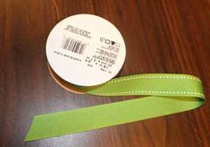 a roll of green ribbon sitting on top of a wooden table next to a tape