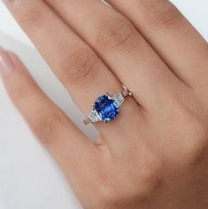 a woman's hand with a ring on it and a blue stone in the middle