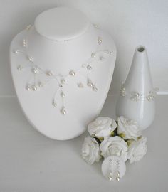 a white necklace and vase with flowers on it