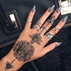 a woman's hand with tattoos and rings on it