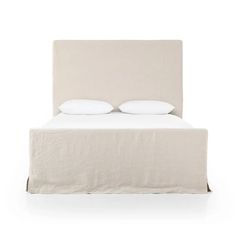 a bed with two pillows on top of it and white sheets in front of the headboard