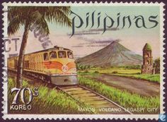 a postage stamp with an image of a train on the tracks and mountains in the background