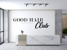 a white marble counter in front of a wall with the words good hair clubs written on it