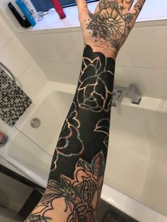 a person's arm with tattoos on it in front of a bathtub and sink