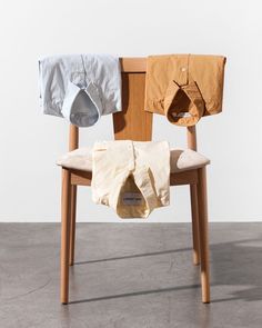 a wooden chair with clothes hanging from it's back and two shirts on the back