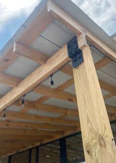 a close up of a wooden structure with metal bells on it's side and sky in the background