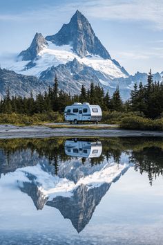 an rv is parked in front of a mountain lake