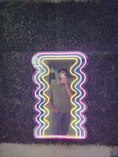 a man is taking a selfie in front of a wall covered with green plants