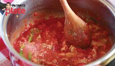 a wooden spoon in a pot filled with red sauce