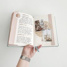 a hand holding an open book with pictures on the pages and writing in it,