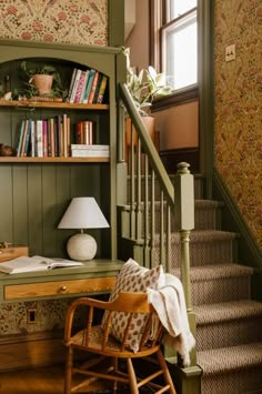 a chair sitting in front of a book shelf next to a stair case filled with books