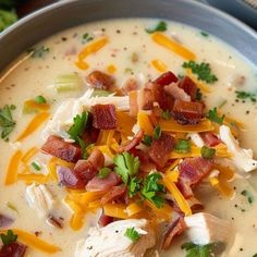 a close up of a bowl of soup with bacon and cheese on top, garnished with parsley