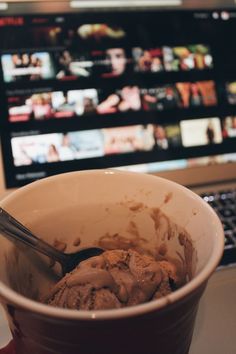 a bowl of ice cream with a spoon in front of a laptop