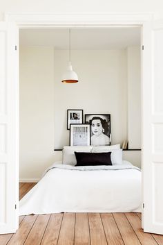 a white bed sitting inside of a bedroom next to two framed pictures on the wall