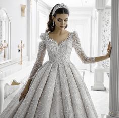 a woman in a wedding dress standing next to a pillar with her hands on her hips