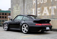 a black sports car parked in front of a rusted building with graffiti on it