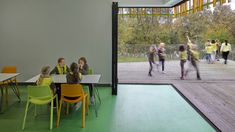 children are sitting at tables and chairs in an open area