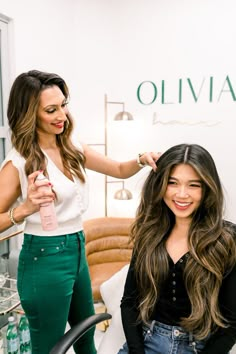 two women are getting their hair done in a beauty salon and one is holding a bottle of water