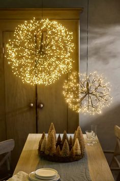 a wooden table topped with plates and a cake next to a lighted christmas wreath hanging from the ceiling