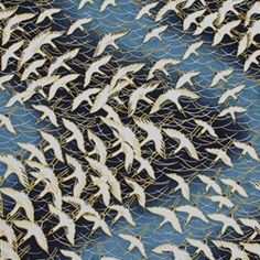 many white birds are flying in the air over some blue and gold mesh fabric,