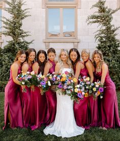 a group of women standing next to each other in front of a building with flowers