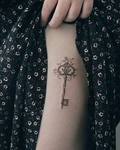 a person with a tattoo on their arm holding a key