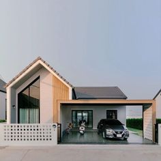 a car is parked in front of a house with a white fence and two cars on the driveway