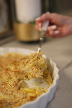 a person scooping some food out of a casserole dish with a spoon