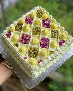 a hand holding a cake with flowers on it