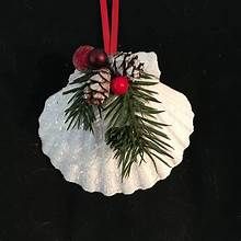 a christmas ornament hanging from a red ribbon on a white plate with pine cones and berries