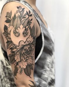 a woman's arm with flowers and leaves tattooed on the arm, in black and white