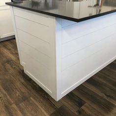 an island in the middle of a kitchen with black counter tops and white cabinetry