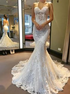 a woman standing in front of a mirror wearing a wedding dress