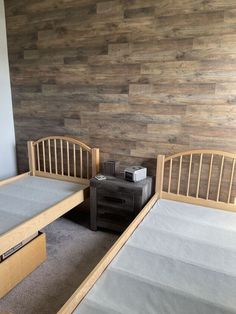 two twin beds in a room with wood paneling on the wall and carpeted floor