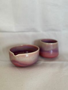 two small cups sitting on top of a white table