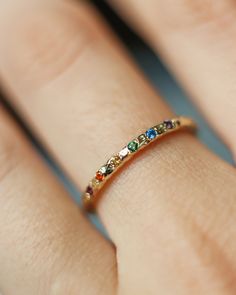 a woman's hand with a gold ring that has different colored stones on it