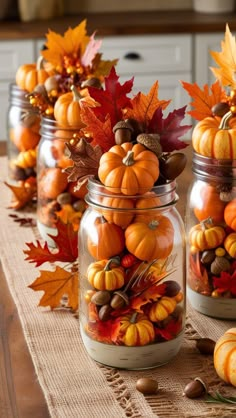 some glass jars filled with pumpkins and leaves