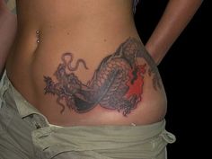 a woman with a dragon tattoo on her stomach is standing in front of the camera