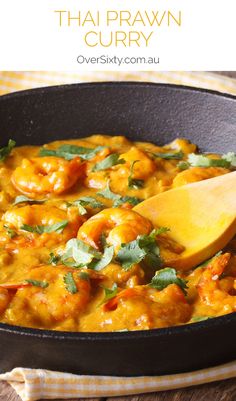 thai prawn curry in a skillet with a wooden spoon on the side