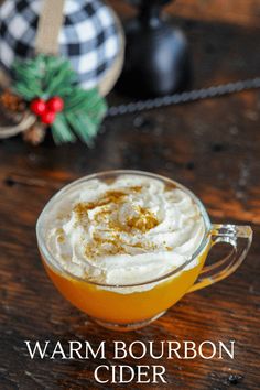 warm and creamy bourbon cider with whipped cream in a glass mug on a wooden table