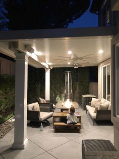 a woman sitting on top of a couch under a covered patio