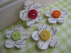 four flower shaped buttons sitting on top of a green and white checkered table cloth