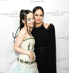 two women standing next to each other in front of a white wall with the words the camera boy foundation on it