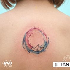 the back of a woman's shoulder with a small origami boat on it