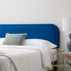 a blue headboard on a bed with white sheets and pillows in a bedroom setting