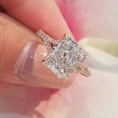 a close up of a person's hand holding a diamond ring