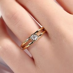 a woman's hand with two gold rings and a diamond in the middle, on top of her finger